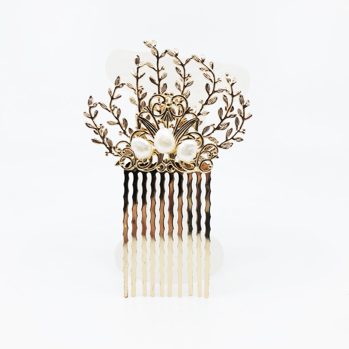 The Vine Hair Comb is a beautiful and versatile piece of jewelry that is perfect for adding a touch of elegance and whimsy to any outfit. The comb is gold plated and features baroque pearls, as well as solid wire wrap work that guarantees its reliable quality. The comb has the perfect size for holding the hair in place. The vine design of the comb is associated with elegance and the otherworldly beauty of elves and greek mythology.