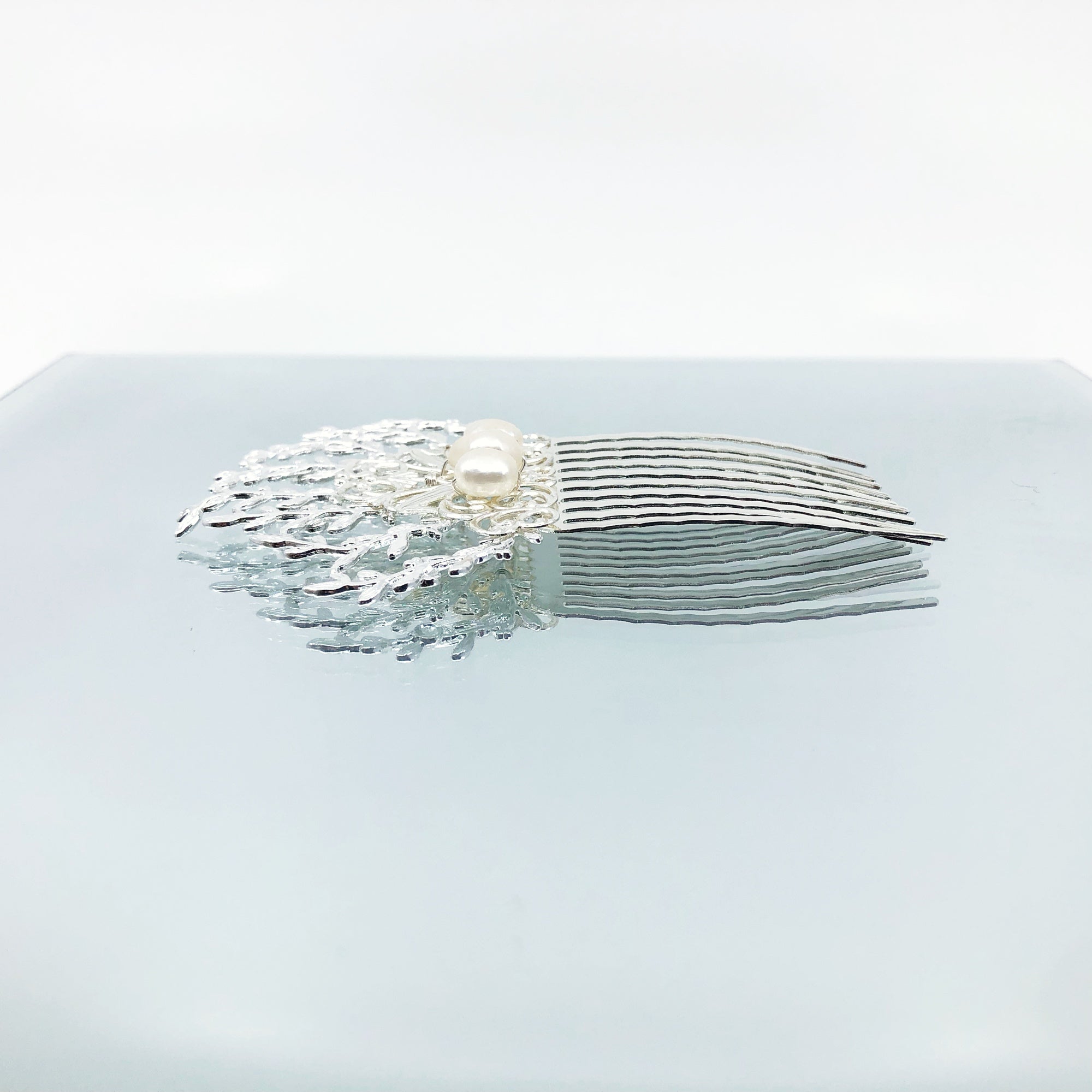 The Vine Hair Comb is a beautiful and versatile piece of jewelry that is perfect for adding a touch of elegance and whimsy to any outfit. The comb is silver plated and features faux pearls, as well as solid wire wrap work that guarantees its reliable quality. The comb has the perfect size for holding the hair in place. The vine design of the comb is associated with elegance and the otherworldly beauty of elves and greek mythology.